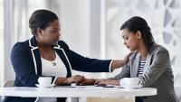 A woman consoling a coworker that is upset.